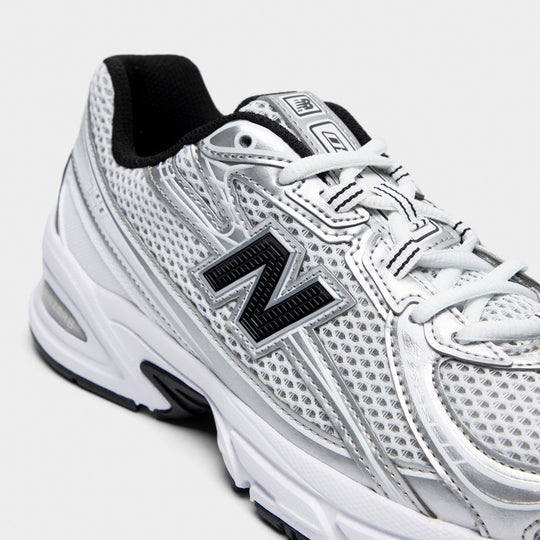New Balance 740. Close-up of white, silver metallic and black sneaker showing white laces, mesh panels and black N logo.