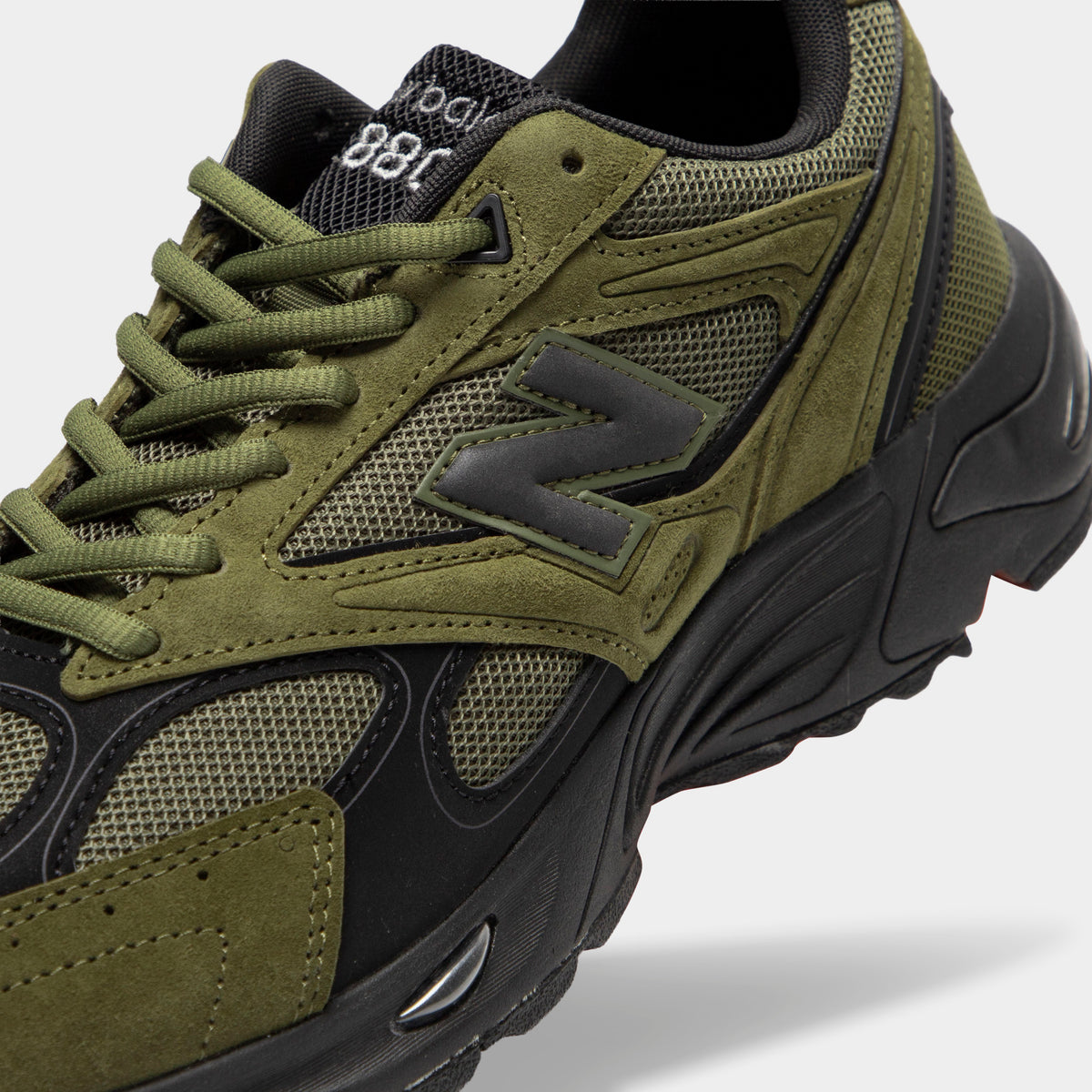 New Balance 880. Close-up view of tongue and lacing highlighting wakame olive green suede overlays, dark mesh base, black trim, wakame green laces, and black mesh tongue with embroidered branding details. 