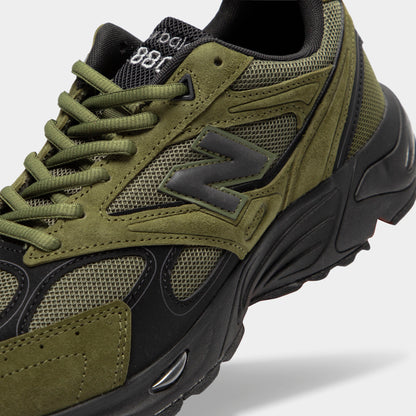 New Balance 880. Close-up view of tongue and lacing highlighting wakame olive green suede overlays, dark mesh base, black trim, wakame green laces, and black mesh tongue with embroidered branding details. 