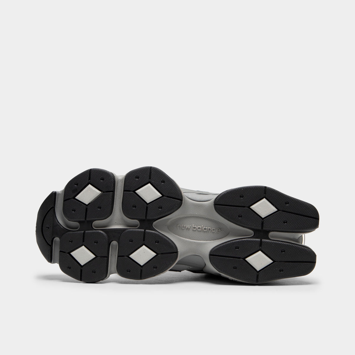  New Balance 9060. Bottom view of single shoe displaying full black rubber outsole featuring signature diamond-shaped pod tread pattern and central shank. 