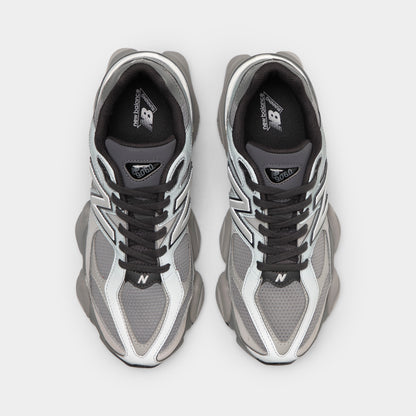 New Balance 9060. Top-down overhead view of a pair of sneakers displaying harbor grey mesh toe boxes with slate grey suede toe overlays, dark grey laces, dark grey tongues with triangular "NB 9060" jewel patches, and black insoles with white logo prints. 