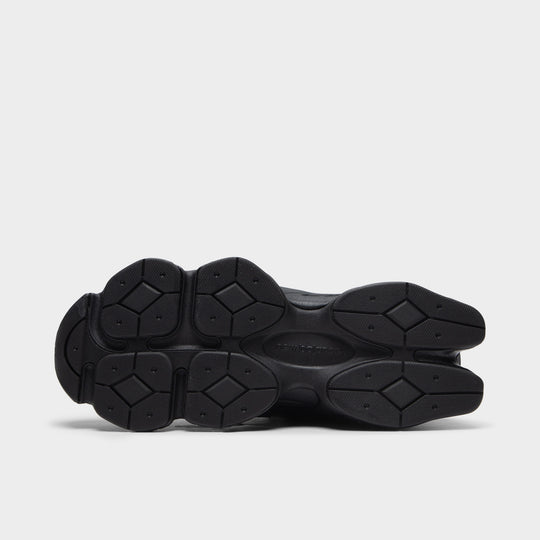 New Balance 9060. Bottom view of black and phantom sneaker showing segmented outsole with circular tread sections.
