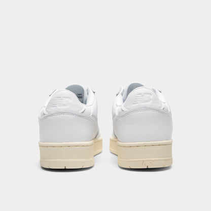 New Balance 950. Rear view of a pair of low-top sneakers displaying white leather heel counters with debossed "NB" logos, white padded collars, and off-white aged rubber midsoles. 