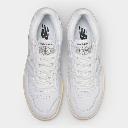 New Balance 950. Top-down overhead view of a pair of low-top sneakers displaying white leather toe boxes with toe cap perforations, white laces, leather tongues with basketball logo patches, and white insoles with dark "NB" branding. 