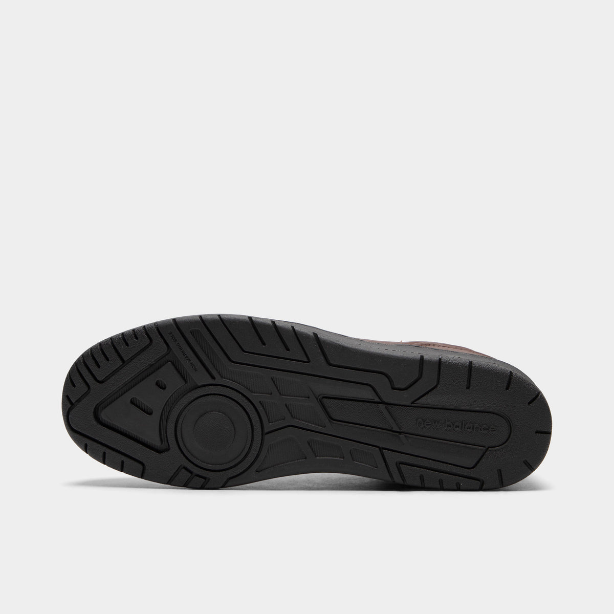 New Balance 950. Bottom view of single shoe displaying full black rubber outsole with multidirectional tread pattern and center New Balance logo. 