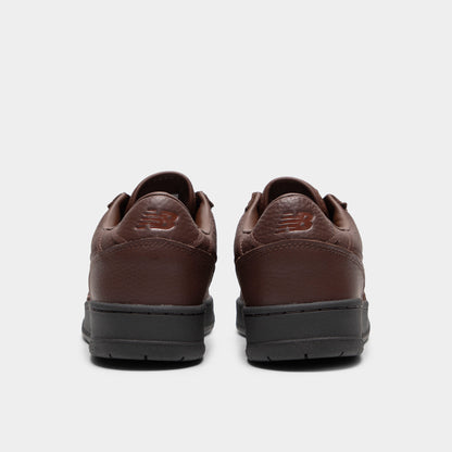 New Balance 950. Rear view of a pair of low-top sneakers displaying dark brown tumble leather heel counters with debossed "NB" logos, dark brown padded collars, and black rubber midsoles. 